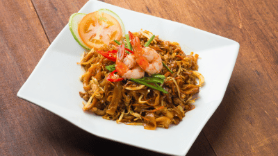 Char Kway Teow, a popular Malaysian stir-fried noodle dish, is made with flat rice noodles, prawns, eggs, bean sprouts, and chives, all cooked in a smoky, flavorful sauce.