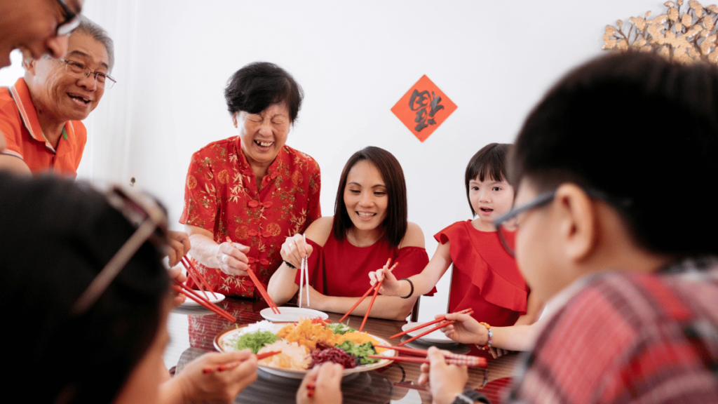 During Chinese New Year celebrations, the Chinese community showcases the cultures and traditions in Malaysia by wearing traditional attire such as the changshan for men and the cheongsam for women, reflecting elegance and cultural heritage.