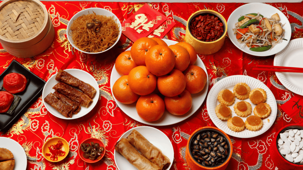 During Chinese New Year, must-have foods include yu sheng (prosperity toss salad), nian gao (sticky rice cake), and mandarin oranges, symbolizing prosperity, unity, and good fortune.