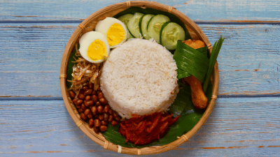 Nasi Lemak, often enjoyed for breakfast, is a fragrant coconut milk rice served with sambal, anchovies, peanuts, eggs, and optional meat or seafood.