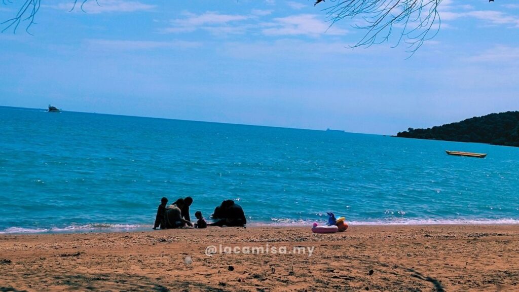 Parents and children enjoying a beach day while building sandcastles along the shore, with their floats visible nearby.
