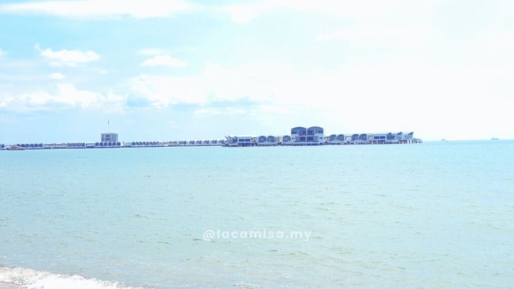 A wide view of the ocean from Monkey Bay Beach showing the Lexis Hibiscus Port Dickson resort villas stretching across the horizon.