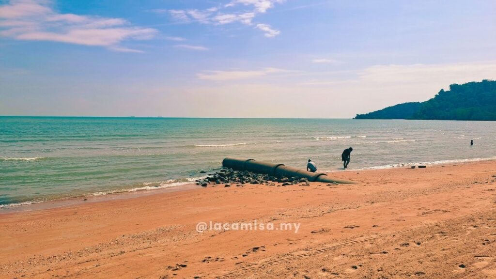 Visitors strolling by the shoreline at Monkey Bay Beach, Port Dickson, Negeri Sembilan.